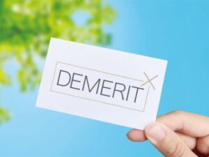 緑の木々と青空を背景にDEMERITと書かれたカード
